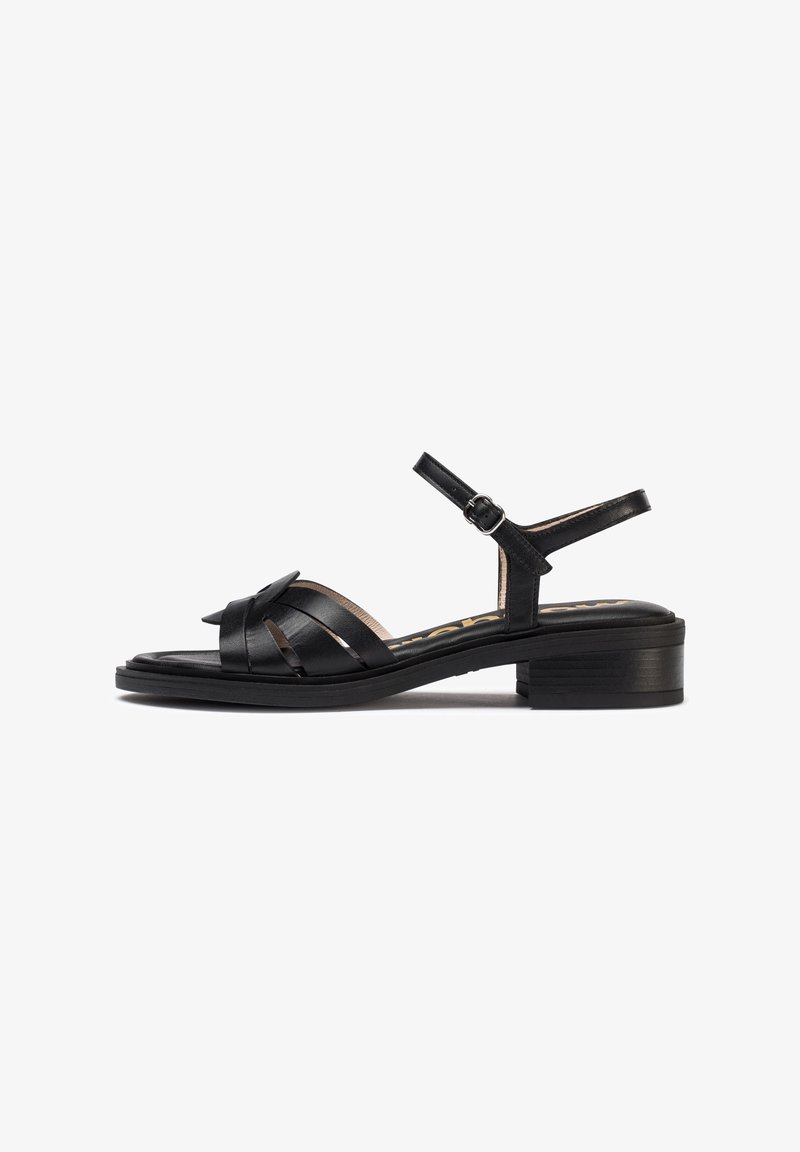 Sandal en cuir noir avec plusieurs lanières entrecroisées, une bride à la cheville avec boucle et un talon bas. Texture lisse et design classique.