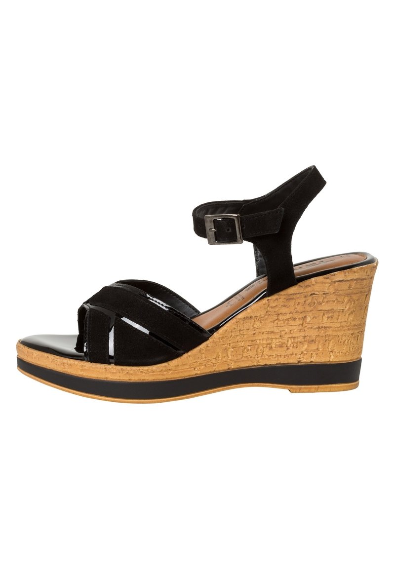 Sandalias de cuña negras con un tacón de corcho texturizado, punta abierta y tira en el tobillo. La parte superior presenta una combinación de ante mate y acentos brillantes.