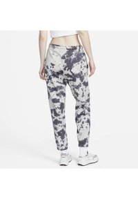 Šedé a bílé tie-dye tepláky s elastickým pasem a manžetami na kotnících. Vyrobené z měkké látky, mají volný střih a kapsy.