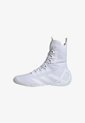 Zapatilla deportiva alta blanca con parte superior de malla texturizada, cordones planos y suela de goma que presenta tres franjas icónicas en el lateral.