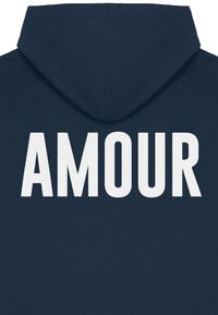 Tumši zils kapucis ar lielu baltu blokpārklājumu uzrakstu "AMOUR" centrā uz muguras. Materiāls izskatās mīksts ar gludu tekstūru.