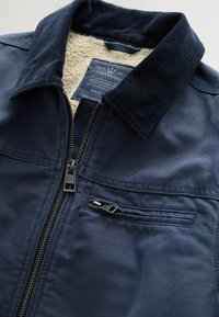 Chaqueta de marina con cuello de pana y forro de forro polar. Cuenta con un cierre frontal y un bolsillo en el pecho con cremallera. Etiqueta adjunta en el interior.