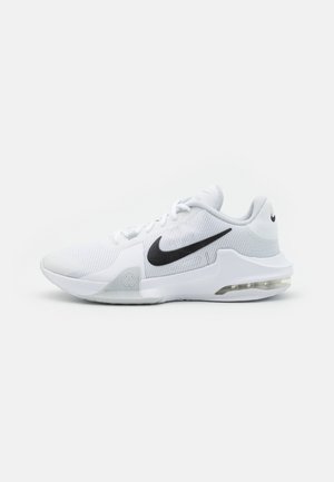 Zapatilla deportiva blanca de Nike con logo swoosh negro, parte superior de malla, suela acolchada y unidad de aire visible en el talón, mostrada de perfil lateral.