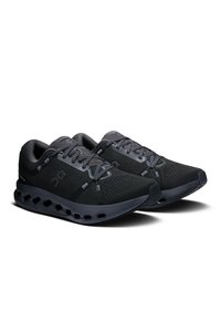 Des chaussures de sport noires avec un dessus en maille respirante, un léger rembourrage et une semelle épaisse dotée de sections découpées pour un amorti.