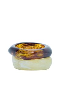 Dos anillos entrelazados hechos de resina translúcida. El anillo superior es de color ámbar-marrón, con un patrón en espiral; el anillo inferior es de color amarillo pálido.