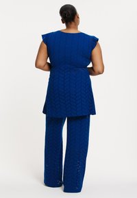 Blauwe tuniek en bijpassende broekset, gemaakt van textuurstof met een ruitpatroon, met korte mouwen en een vloeiende silhoët.