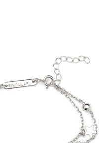 Pulsera de plata con cadena ajustable, etiqueta grabada que dice "SINGULARU" y elementos decorativos que incluyen una estrella y una bola.