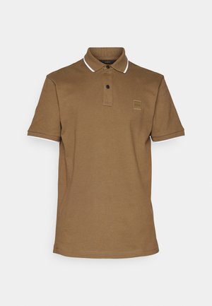 Polo marrone con colletto, bordino bianco sulle maniche, chiusura a due bottoni e una piccola etichetta con logo sul petto. Tessuto misto cotone.