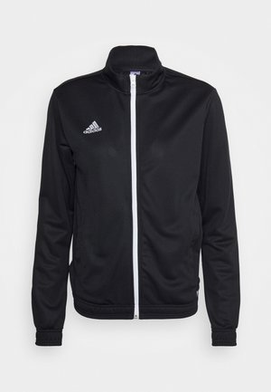 Juodas zip-up švarkas su aukštu kaklu, pagamintas iš lygaus audinio. Yra baltas užtrauktukas ir baltas "adidas" logotipas kairėje krūtinės pusėje.