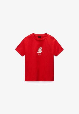 Rotes T-Shirt mit kurzen Ärmeln und einem kleinen weißen Cartoon-Charakter sowie dem Text "Wrong things right attitude" in der Mitte auf der Vorderseite gedruckt.