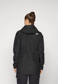 Black waterproof jacket with a hood, cinched waist, and long sleeves. Features the logo on the upper back. Smooth, matte texture.