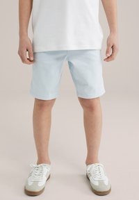 Svetlomodré bavlnené šortky so strihaním po rovne, s prehnutým lemom a jemnou textúrou, zlúčené s bielymi a šedými teniskami.