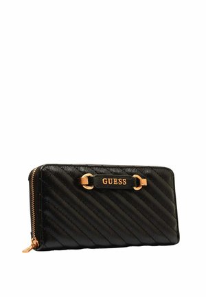 Portefeuille Guess en cuir matelassé noir avec fermeture éclair et plaque logo dorés sur le devant, vue en angle sur fond blanc.