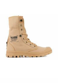 Bottine en toile beige avec un bout rond, lacets sur le devant, semelle en caoutchouc renforcée et logo sur le côté extérieur.
