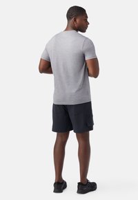 Grijze t-shirt met korte mouwen en een ronde hals, gecombineerd met zwarte cargo shorts. De stof lijkt glad met een iets gestructureerde afwerking.