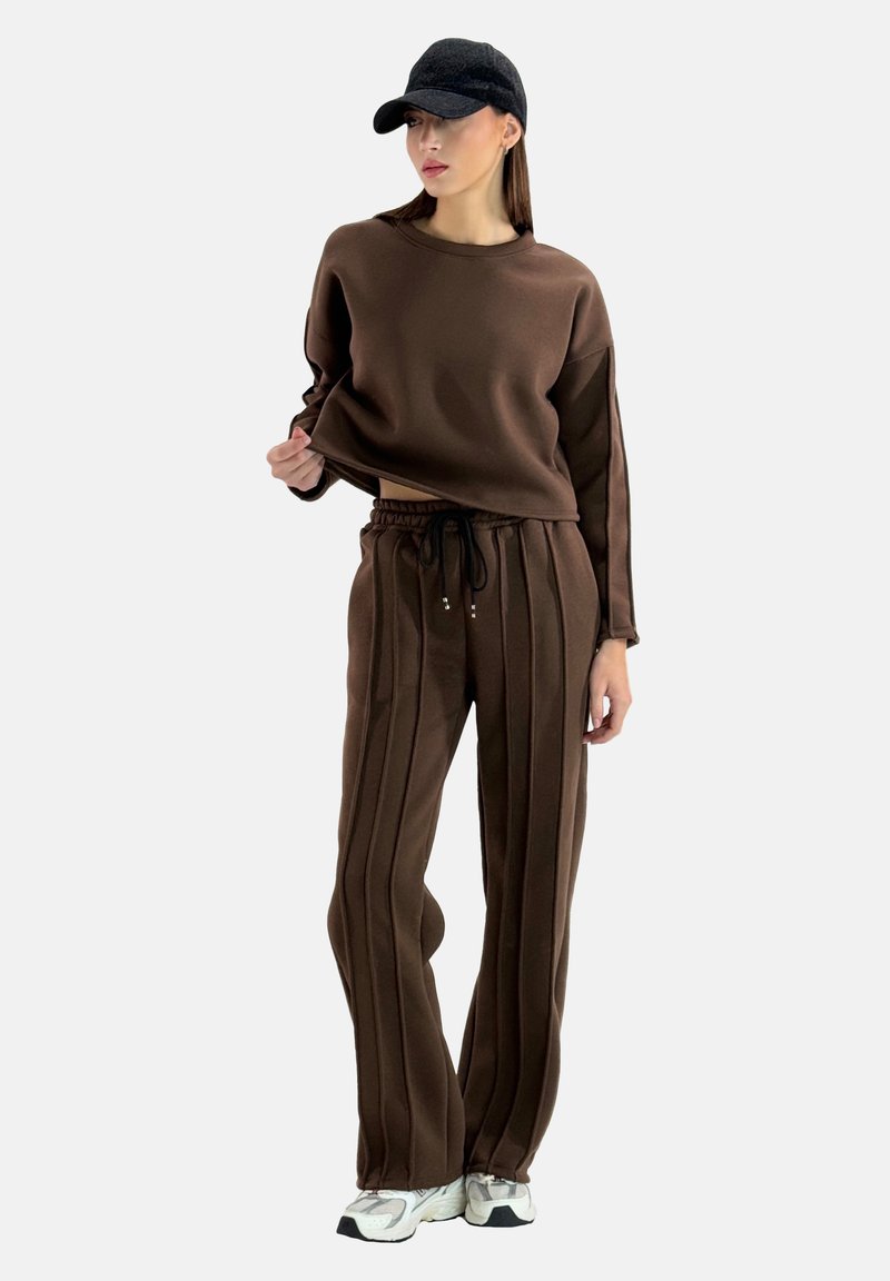 Bruin sweatshirt en bijpassende broek gemaakt van zachte stof. Sweatshirt heeft een relaxte pasvorm; de broek heeft verticale strepen en een elastische tailleband.