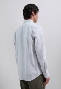 Wit gestreept overhemd met een button-down kraag, lange mouwen, getailleerde pasvorm en een afgeronde zoom. Zachte stof en subtiel textuurdetail.