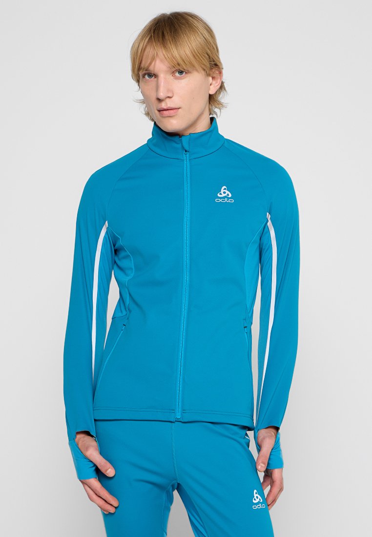 Turkusowa kurtka sportowa z wysokim kołnierzem, pełnym zamkiem i białymi paskami po bokach. Wykonana z gładkiego, elastycznego materiału. Logo marki na piersi.