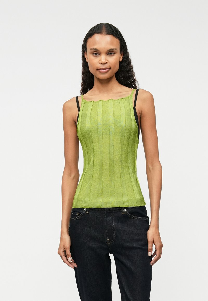 Zielona, prążkowana bluzka na ramiączkach z falbaniastym dekoltem i cienkimi czarnymi sznurkami. Dopasowany krój o gładkiej fakturze, zestawiona z ciemnymi dżinsami.