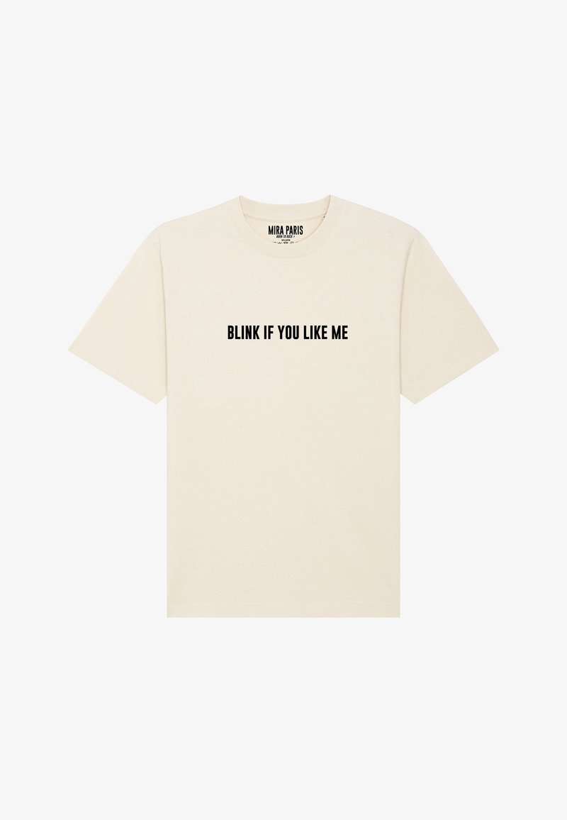 Crème T-shirt met korte mouwen en een ronde hals. Voorzien van gedurfde zwarte tekst met de tekst "KNIP MET JE OGEN ALS JE MIJ LEUK VINDT" op de voorkant.