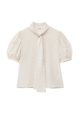 Blouse crème à petits pois, manches courtes bouffantes et détail de nouage à l'encolure devant.