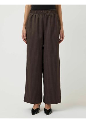 Brune vidbukse bukser med smale striper og elastisk linning, brukt med svarte spisse hæler, vist fra midje til føtter.