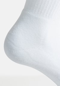 Calzino di cotone bianco che mostra una texture a costine con una finitura liscia. Presenta una punta e un tallone rinforzati per una maggiore durata.