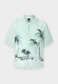Φωτεινό πράσινο πουκάμισο με κοντά μανίκια και κουμπιά, με μαύρο και λευκό μοτίβο φοίνικα και τροπικά λουλούδια στο κάτω μέρος.