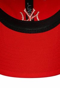 Rote Basecap mit schwarzem Schirm, mit weißen gestickten Logodetails. Der Stoff hat eine strukturierte Oberfläche, und die Nähte sind sichtbar.