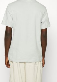 Light gray cotton t-shirt with short sleeves, a relaxed fit, and a classic crew neckline, paired with beige relaxed-fit shorts.