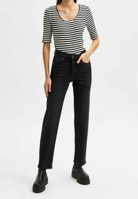 Randig svart och vit ribbad topp med korta ärmar, i kombination med högmidjade svarta raka jeans och svarta kraftiga stövlar.