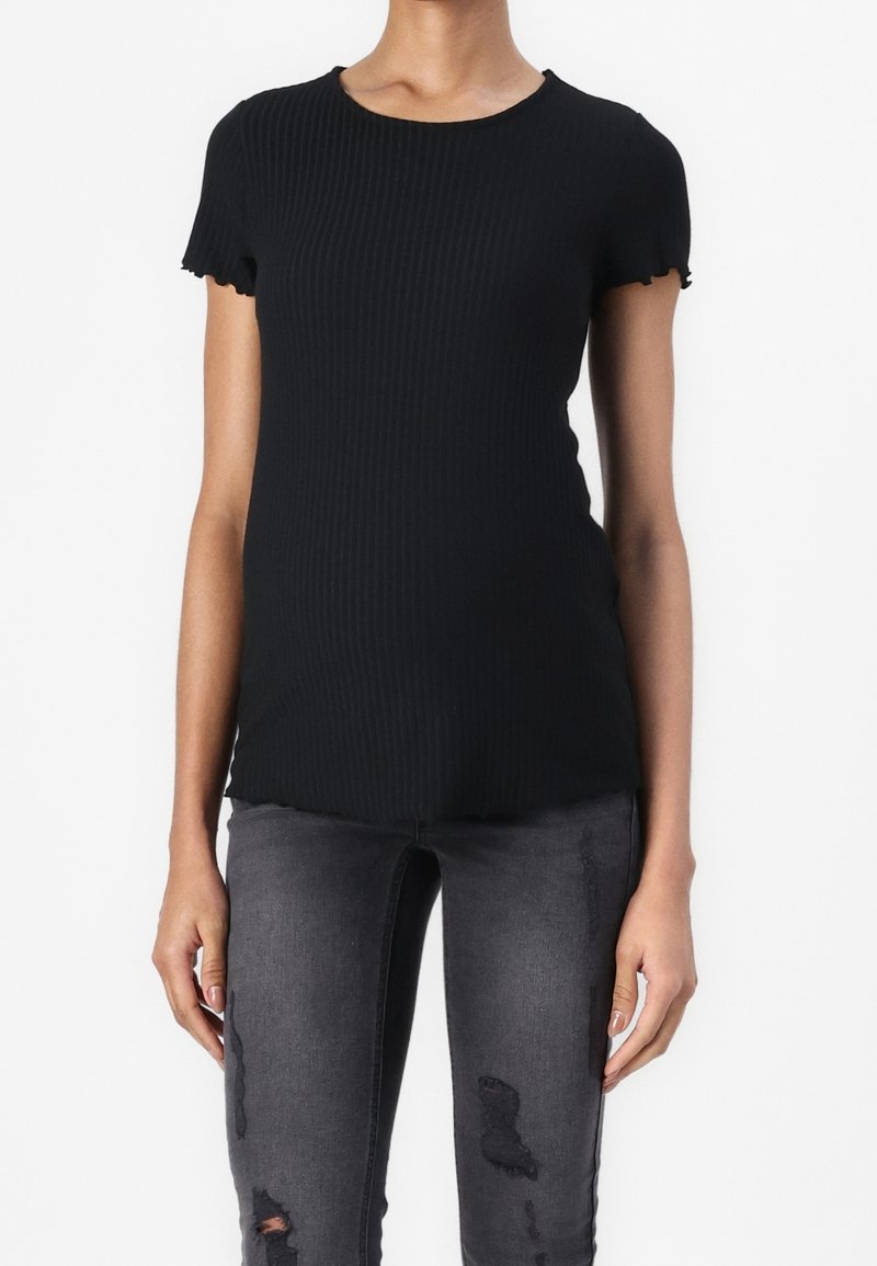 Mustat ribbattu äitiys t-paita, jossa on lyhyet, röyhelöillä varustetut hihat, pyöreä pääntie ja vartalonmyötäinen malli, yhdistettynä kulutettuihin harmaisiin skinny-farkkuihin.