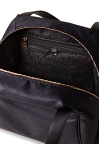 Zaino nero con un esterno testurizzato, cerniera dorata e un ampio interno che presenta una tasca con cerniera e un motivo foderato.