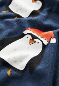 Fleece-Stoff mit einem blauen Hintergrund und Cartoon-Pinguinen; einer trägt einen roten Weihnachtsmann-Hut, mit einer strukturierten und weichen Oberfläche.