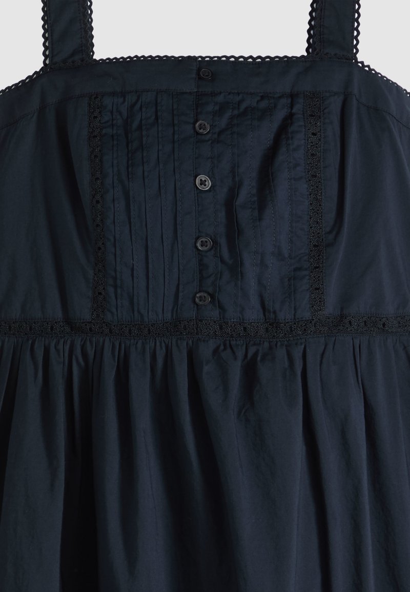 Corsage de robe noire sans manches avec fermeture à boutons sur le devant, détails de plis verticaux et bordure en dentelle le long des bretelles et des coutures.