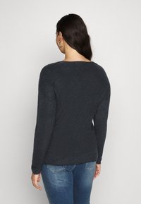 Dark gray knitted sweater with a relaxed fit, long sleeves, and a round neckline. The texture appears soft and slightly fluffy.