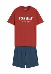 Czerwona bawełniana koszulka z białym napisem "MOGĘ SPAĆ CAŁY DZIEŃ" w połączeniu z niebieskimi, lekkimi szortami. Prosty krój, okrągły dekolt, casualowy fason.