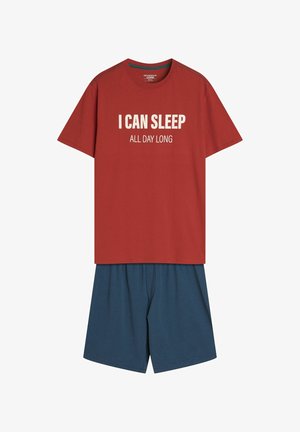 Czerwona bawełniana koszulka z białym napisem "MOGĘ SPAĆ CAŁY DZIEŃ" w połączeniu z niebieskimi, lekkimi szortami. Prosty krój, okrągły dekolt, casualowy fason.