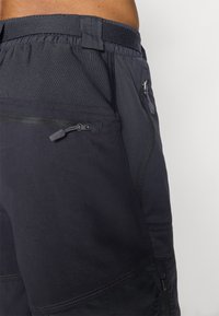 Shorts de sport navy en tissu texturé, avec une taille élastique et une poche latérale zippée pour un rangement sécurisé.