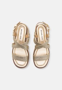 Gold glitter sandals with a rounded toe, cross straps, and buckle closure. Soft metallic insole and padded footbed with a brown sole.