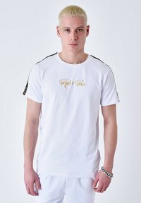Camiseta de algodón blanca con un logo dorado de "Project Paris" en el frente, con detalles y rayas negras a lo largo de los hombros.