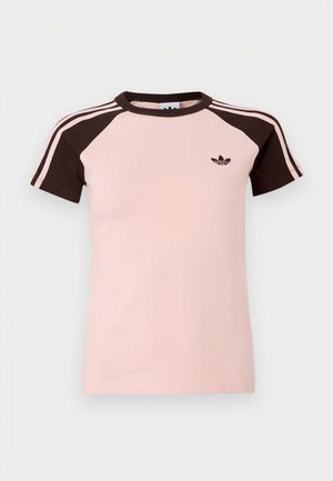 Camiseta de color rosa claro con mangas raglán marrones, que presenta tres franjas marrones en cada hombro y un pequeño logo negro en el pecho.