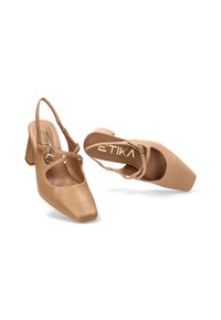Tacones slingback de imitación cuero marrón con punta cuadrada, correa en el tobillo y detalles recortados. El diseño del tacón bloque añade estabilidad.
