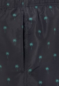 Čierna látka s malými vzormi palm na pozadí v odtieňoch teal; obsahuje elastický pás a šev bočnej vrecka. Textúra sa zdá byť hladká a ľahká.