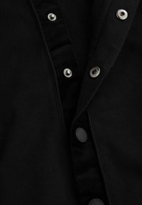 Czarna koszula z tkaniny z srebrnymi zatrzaskami z przodu, z teksturowanym aksamitem przy dekolcie dla dodatkowego efektu.