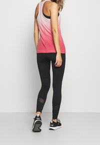 Pink ombre tank top with a racerback design, paired with black leggings featuring mesh accents and black athletic shoes.