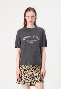 Grauer, gestrickter Pullover mit kurzen Ärmeln und „RACING CLUB��“-Aufdruck, kombiniert mit einem beigen Satinrock im Leopardenmuster. Insgesamt glatte Textur.