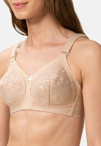 Vaalea pitsinen rintaliivi, jossa on kukkakuosi, pehmeät verkkopaneelit, säädettävät olkaimet ja koristeellinen etulukko. Sileä kangastuntuma.