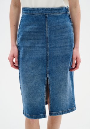 Mid-lang blå denimnederdel med en frontsøm og midterslids, båret af en person med hænder afslappet ved siderne.