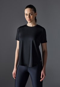 Cămașă sport neagră cu mânecă scurtă, realizată dintr-un material ușor, având un guler rotund și un detaliu subtil al logo-ului la tiv.